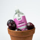 A bottle of Bio-D cleansing hand wash  in plum & mulberry inside a terracotta plant pot with plums inside. This hand wash is available at Babipur.