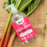 A flatlay image of a 500ml bottle of Bio-D cleansing hand wash  in Yorkshire rthubarb on top of rhubarb on a hessian sheet. This hand wash is available at Babipur.
