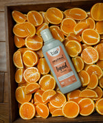 A Bio-D 750ml mandarin washing up liquid bottle in a crate of sliced mandarins. This washing up liquid is available at Babipur 