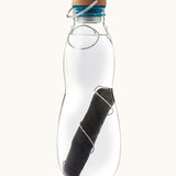 A close up of the Black + Blum glass bottle with active charcoal water filter and locking coil showing the charcoal filter detail