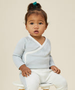A toddler wearing the Mori organic cotton and bamboo kimono bodysuit in a blue stripe design.