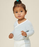A toddler wearing the Mori organic cotton and bamboo kimono bodysuit in a blue stripe design, with some blue stripe joggers.