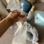 A person holding the top of the Lola&Lykke Smart Electric Breast Pump, with a milk bag attached to show how the bag attaches to the pump. This is perfect for storing breast milk for later