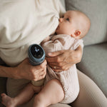 A person breastfeeding their child and using the Lola&Lykke Smart Electric Breast Pump at the same time. 