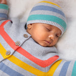 A child wearing the Frugi Bright As A Button Cardi - Grey Marl Stripe, and the same pattern Frugi Hat