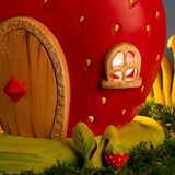 Bumbu handcrafted wooden strawberry plant figure standing next to a wooden strawberry house
