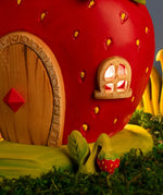 Bumbu handcrafted wooden strawberry plant figure standing next to a wooden strawberry house