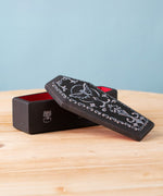 A Bumbu handmade and hand painted wooden black coffin with white detail and red inside with a removable lid available a Babipur.