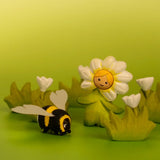 Bumbu wooden daisy flower child figure showing hand painted facial features standing next to a wooden bee