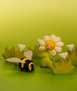 Bumbu wooden daisy flower child figure showing hand painted facial features standing next to a wooden bee