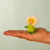 Bumbu wooden daisy flower child figure with hand painted facial features standing on a adult hand