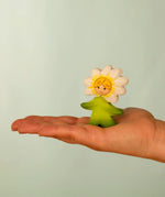 Bumbu wooden daisy flower child figure with hand painted facial features standing on a adult hand