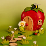 Bumbu wooden daisy flower child figure standing next to a wooden strawberry house with a bee on top and snail