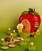 Bumbu wooden daisy flower child figure standing next to a wooden strawberry house with a bee on top and snail