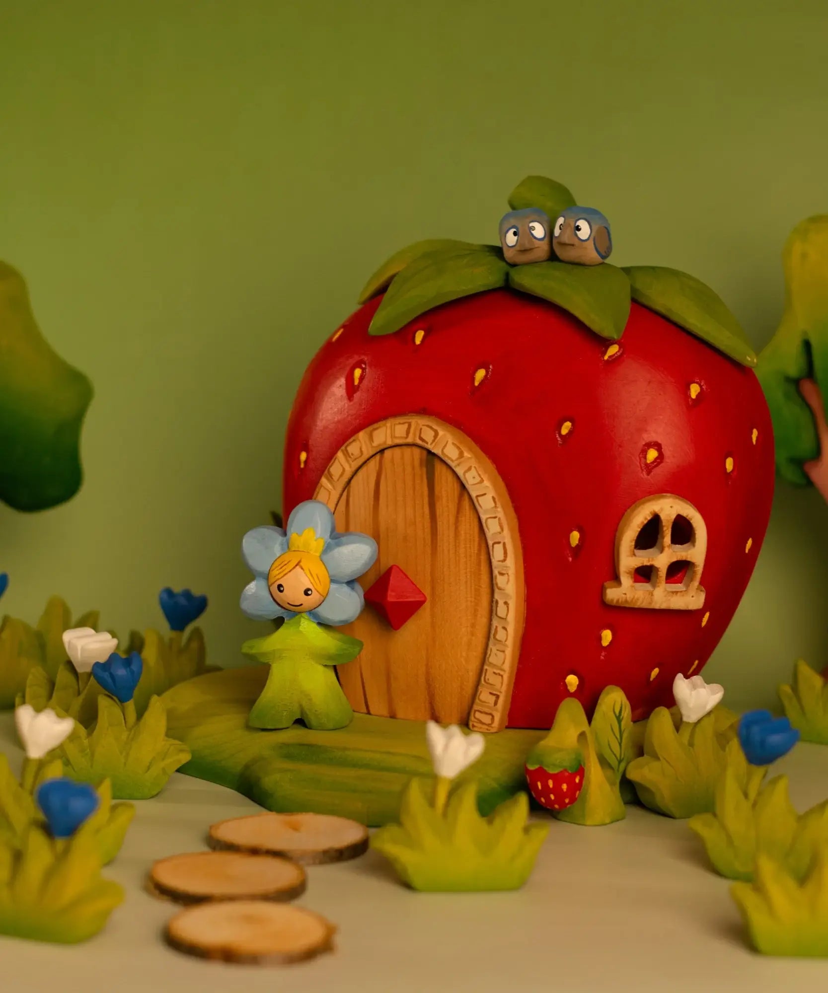 Bumbu wooden forget me not flower child figure standing next to a wooden strawberry house with lovebirds on top 