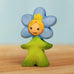 Bumbu handcrafted wooden blue forget me not flower child figure with hand painted facial features standing on a wooden surface