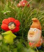 Bumbu wooden red poppy flower child figure next to a wooden gnome figure standing in grass