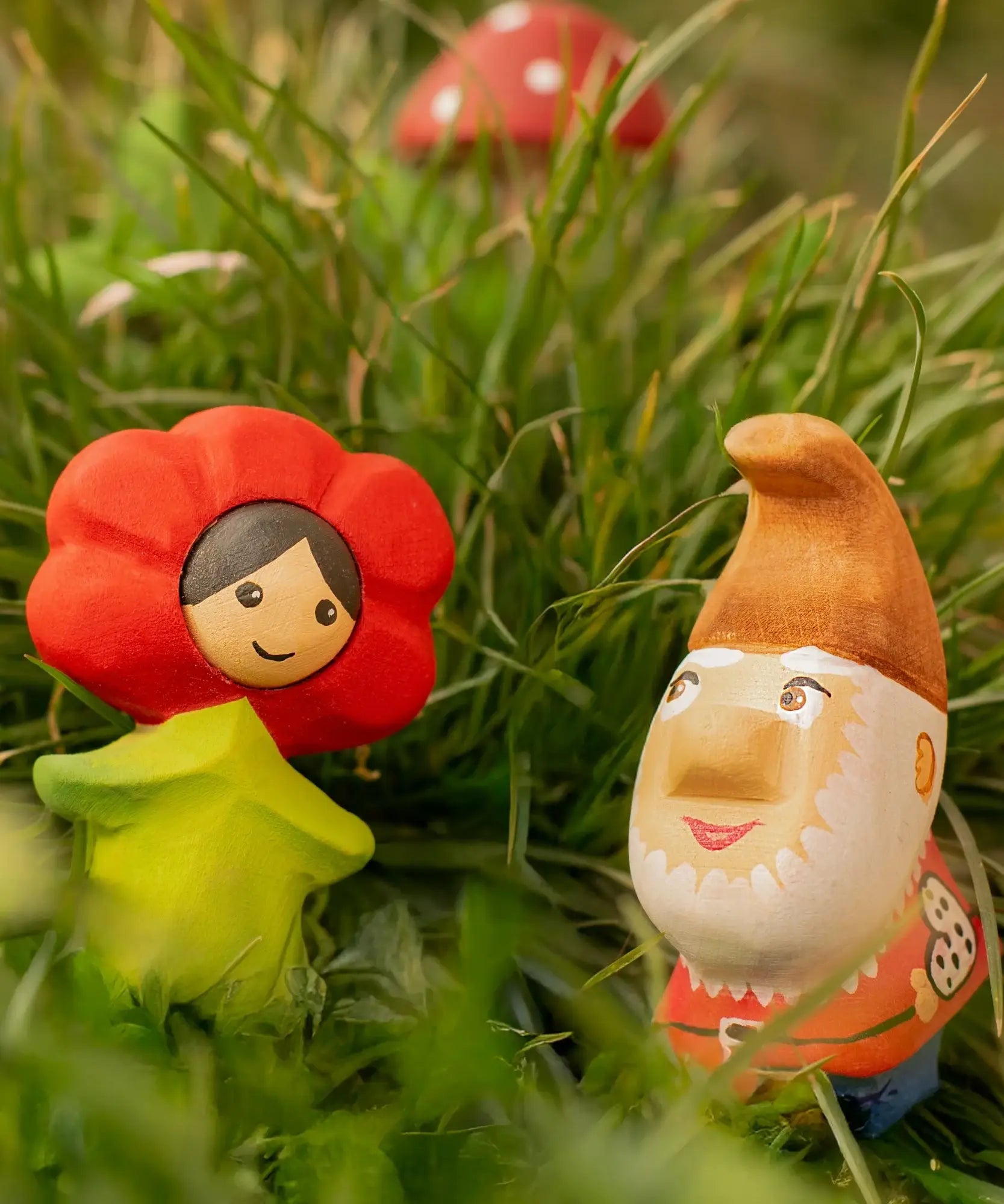 Bumbu wooden red poppy flower child figure next to a wooden gnome figure standing in grass
