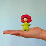 Bumbu wooden red poppy flower child figure standing on a adult hand
