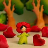Bumbu wooden red poppy flower child figure in a playscene with red wooden hearts and trees in the background