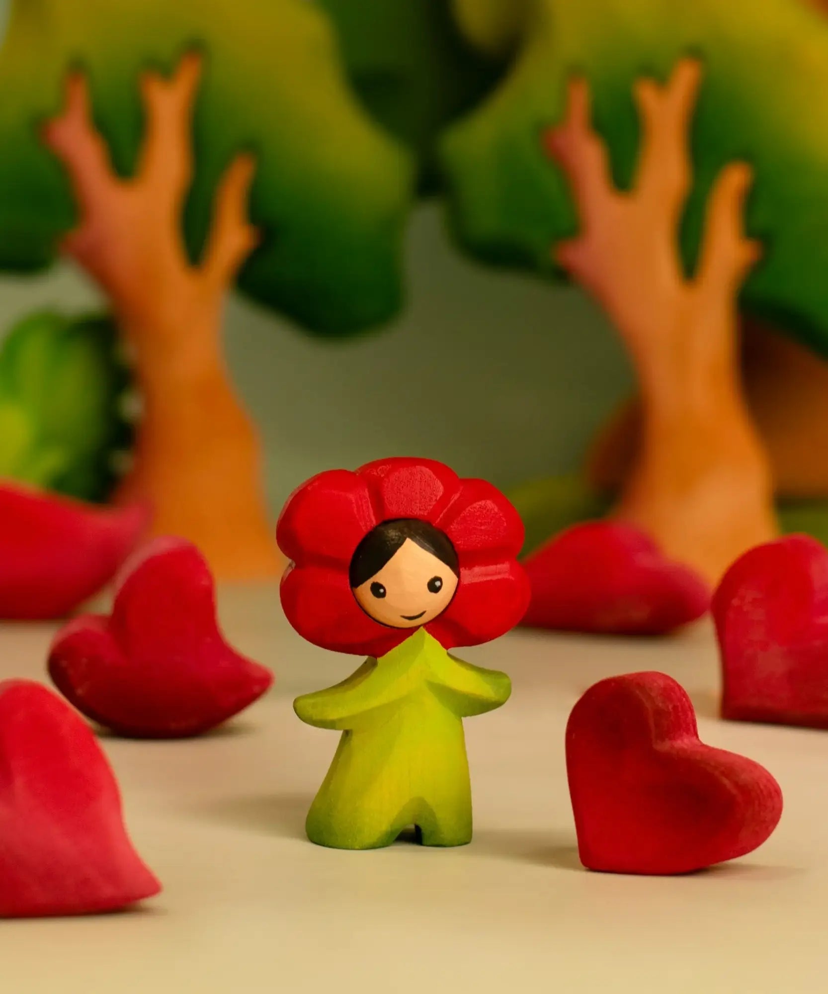 Bumbu wooden red poppy flower child figure in a playscene with red wooden hearts and trees in the background