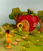 Bumbu wooden sunflower child figure standing next to a wooden strawberry house with a bee on top and orange fairy