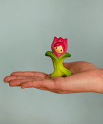 Bumbu wooden pink tulip figure standing on a adult hand