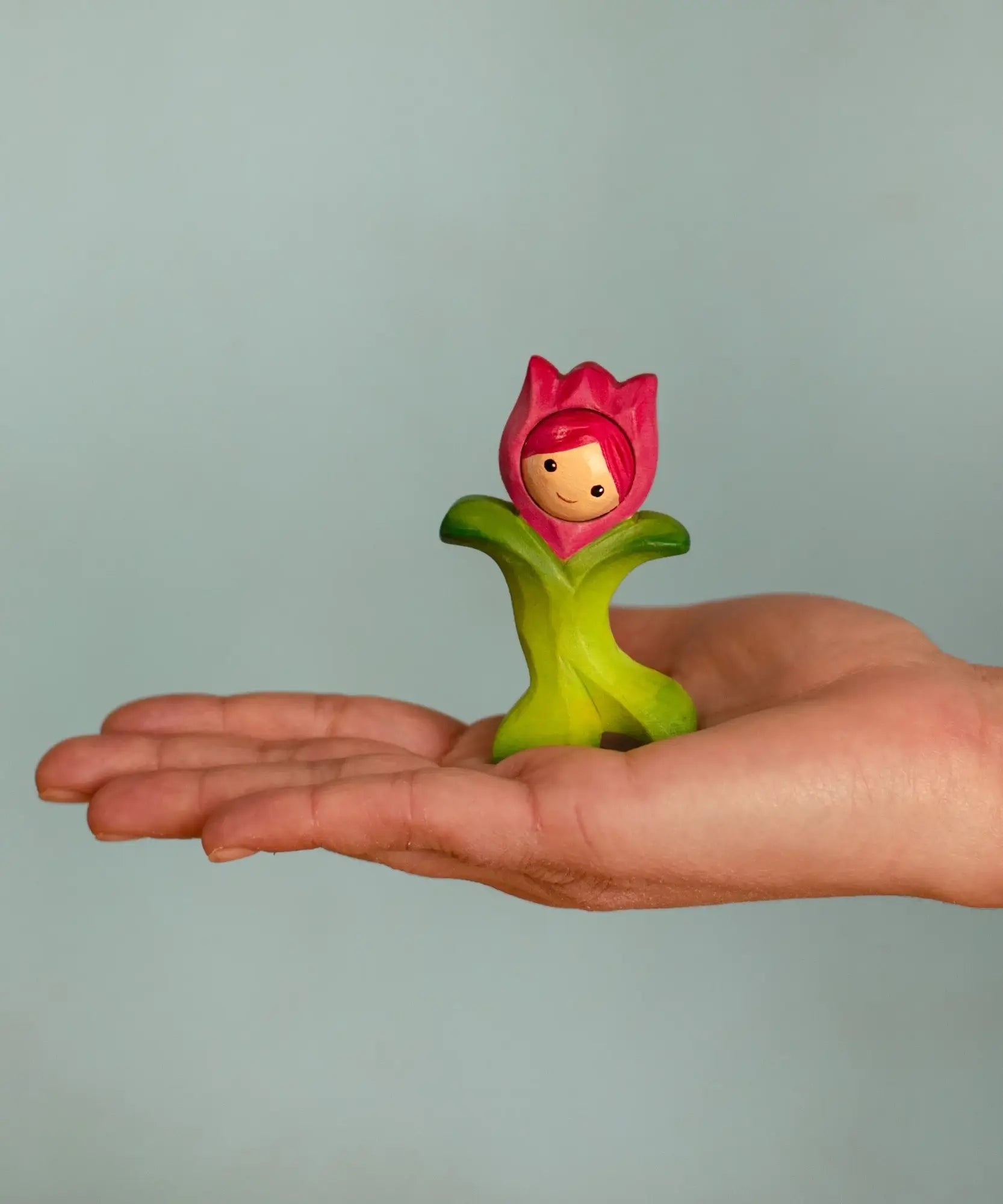 Bumbu wooden pink tulip figure standing on a adult hand