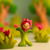 Bumbu wooden pink tulip figure showing hand painted facial features standing next to wooden pink flowers