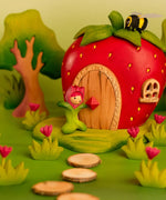Bumbu wooden pink tulip figure standing next to a wooden strawberry house with a bee on top