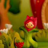 Bumbu wooden pink tulip figure standing next to a wooden strawberry plant