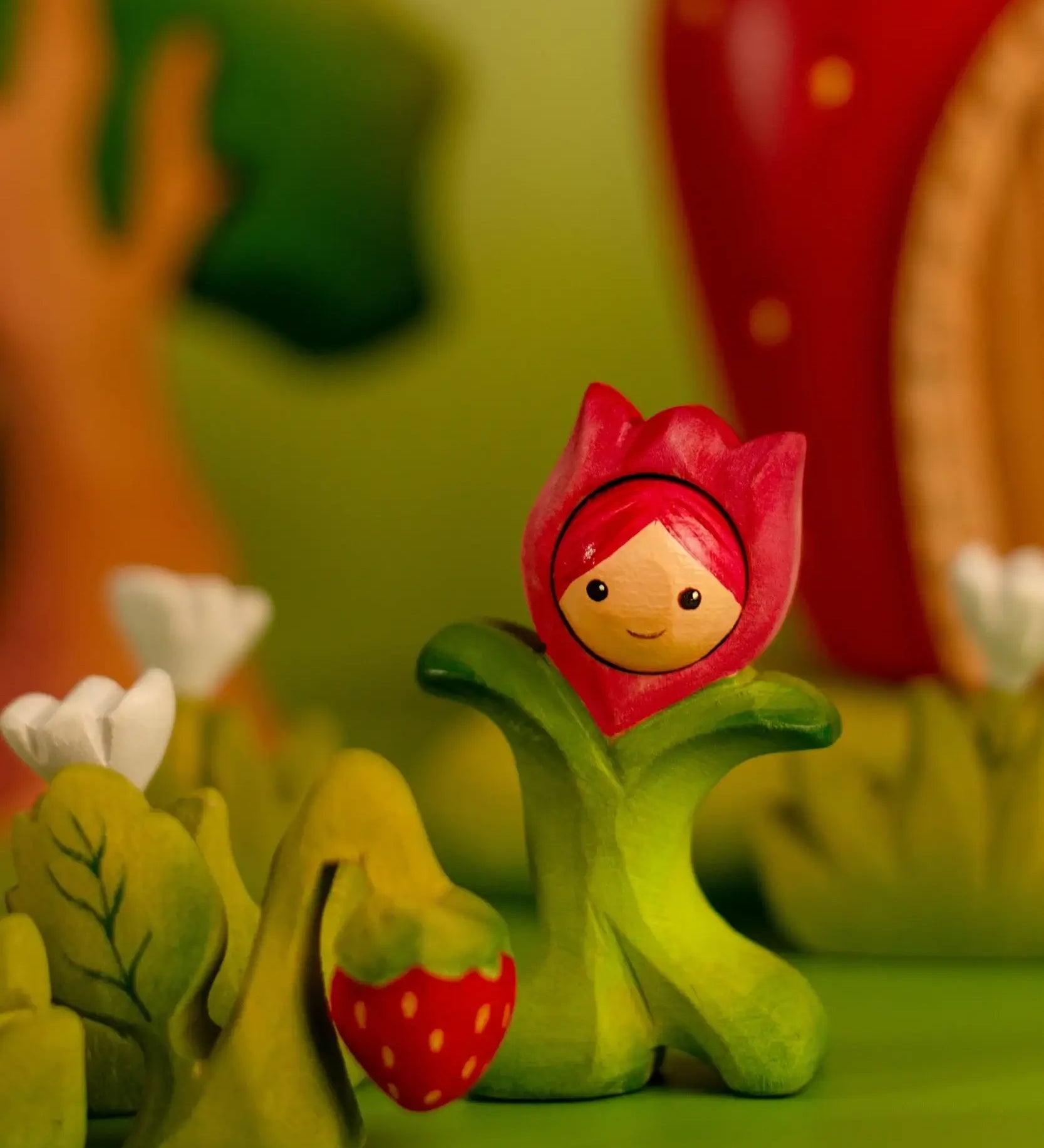 Bumbu wooden pink tulip figure standing next to a wooden strawberry plant