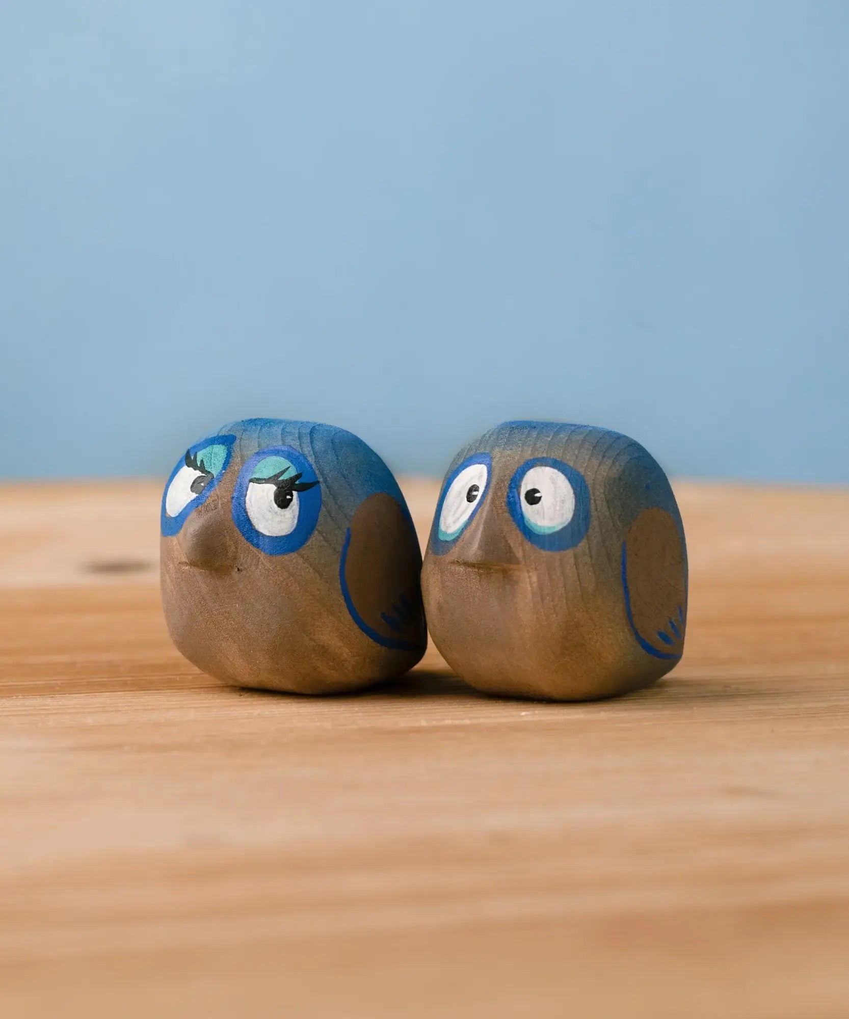 Bumbu hand crafted large wooden love birds figure set standing on a wooden surface.