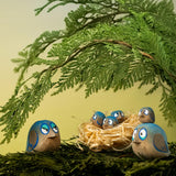 Bumbu hand crafted wooden love birds figures perched on a branch with small birds in a straw nest