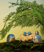 Bumbu hand crafted wooden love birds figures perched on a branch with small birds in a straw nest