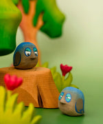 Bumbu hand crafted wooden love birds figure set in a playscene resting on a tree stump