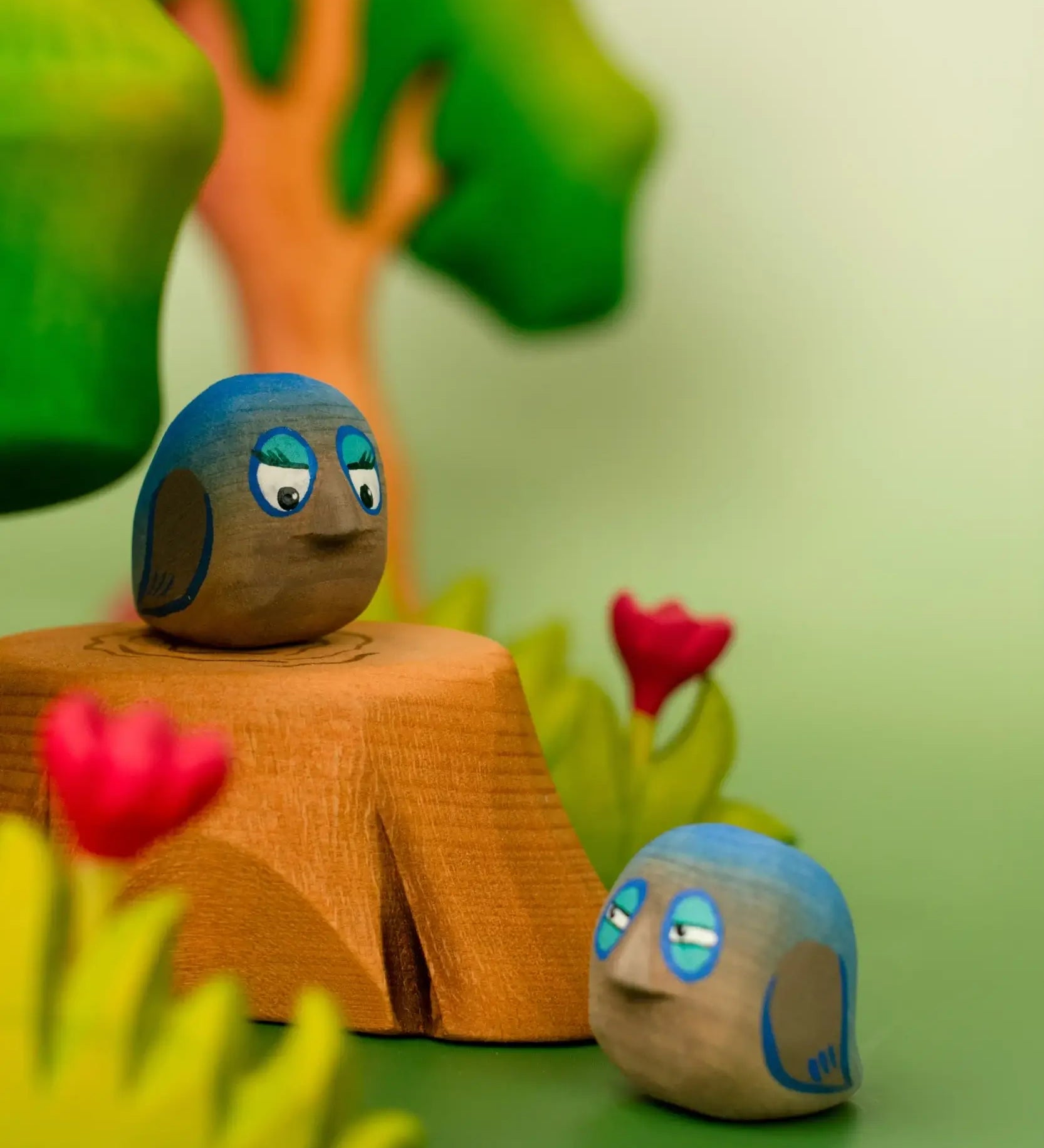 Bumbu hand crafted wooden love birds figure set in a playscene resting on a tree stump