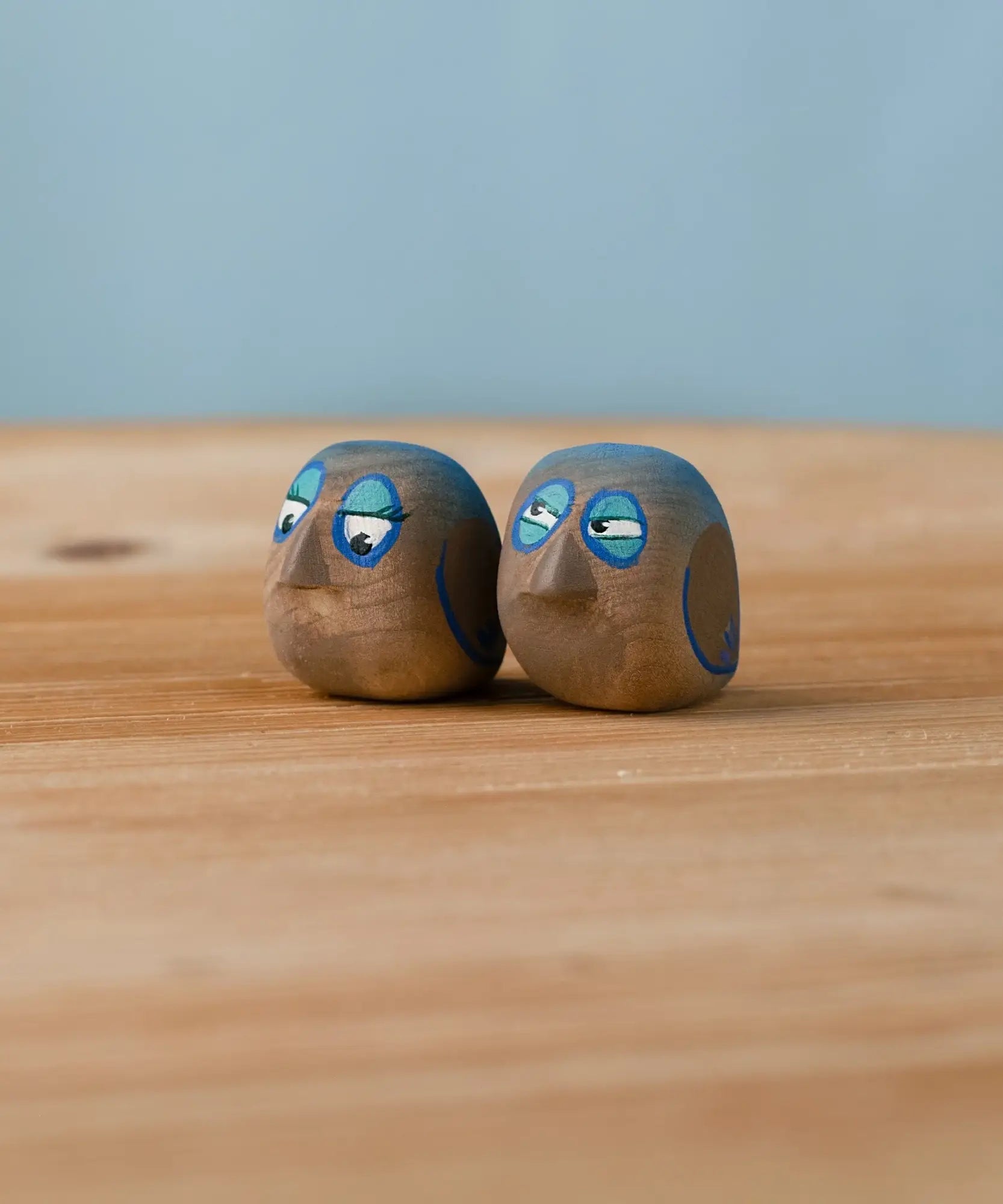 Bumbu hand crafted medium wooden love birds figure set standing on a wooden surface.