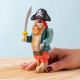 An adult hand holding the Bumbu handmade and hand painted pirate wooden figure showing size