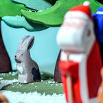A Bumbu grey hare figure is sat under a tree, with the Bumbu Santa in the foreground. The Santa figure is blurry as the hare figure is in focus