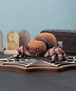 Bumbu handmade and hand painted wooden spider figure with hand painted facial features resting on a wooden Bumbu cobweb in a spooky play scene