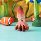 Bumbu handmade and hand painted wooden squid figure with cute painted on eyes with other Bumbu ocean themed figures in the background 