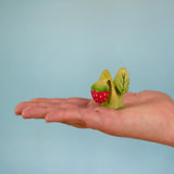 Bumbu handcrafted wooden strawberry plant standing on a adult hand