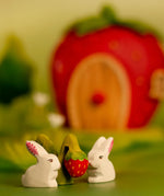 Bumbu handcrafted wooden strawberry plant figure standing next to white rabbit and a strawberry house in the background