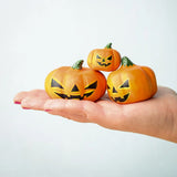 The small, medium and large Bumbu Toys Halloween Pumpkins are being held in a persons palm in a stacked formation