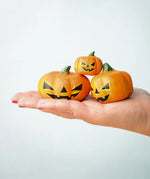 The small, medium and large Bumbu Toys Halloween Pumpkins are being held in a persons palm in a stacked formation
