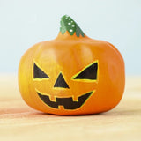 Bumbu Toys Halloween Pumpkin - Medium. The image shows a hand made and hand painted pumpkin figure in orange, with yellow and black facial features and a green and white spotted stem