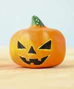 Bumbu Toys Halloween Pumpkin - Medium. The image shows a hand made and hand painted pumpkin figure in orange, with yellow and black facial features and a green and white spotted stem