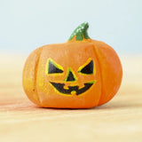 The small Bumbu Toys Halloween Pumpkin is hand made and hand painted in orange, with yellow and black facial features and a green and white spotted stem. This image gives a lose up of the pumpkin grooves, giving it a realistic look