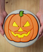 A person holding the Bumbu Toys Halloween Pumpkin Puzzle - Grey, in their hands. The image is a close up view of the pumpkin puzzle from above, showing the different puzzle sections